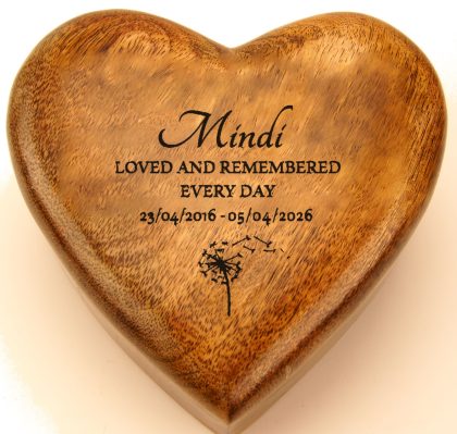 Name, dates and a dandelion drifting away engraved on a mango wood heart urn
